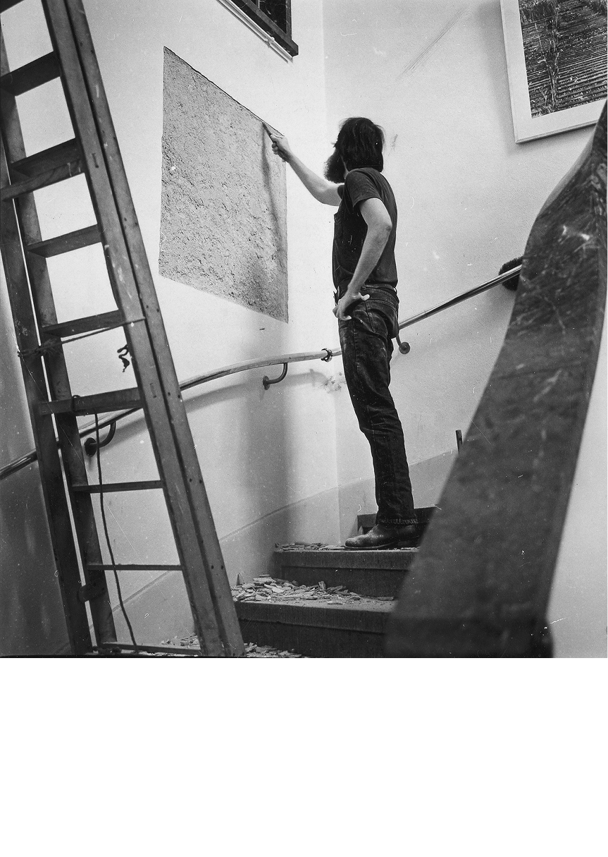 Lawrence Weiner creating A 36" × 36" <em>removal to the lathing or support wall of plaster or wallboard from a wall</em>, 1968, from ‘When Attitudes Become Form’, Kunsthalle, Bern, 1969,collection of the Museum of Modern Art, New York, photograph: Shunk Kender, courtesy Roy Lichtenstein Foundation