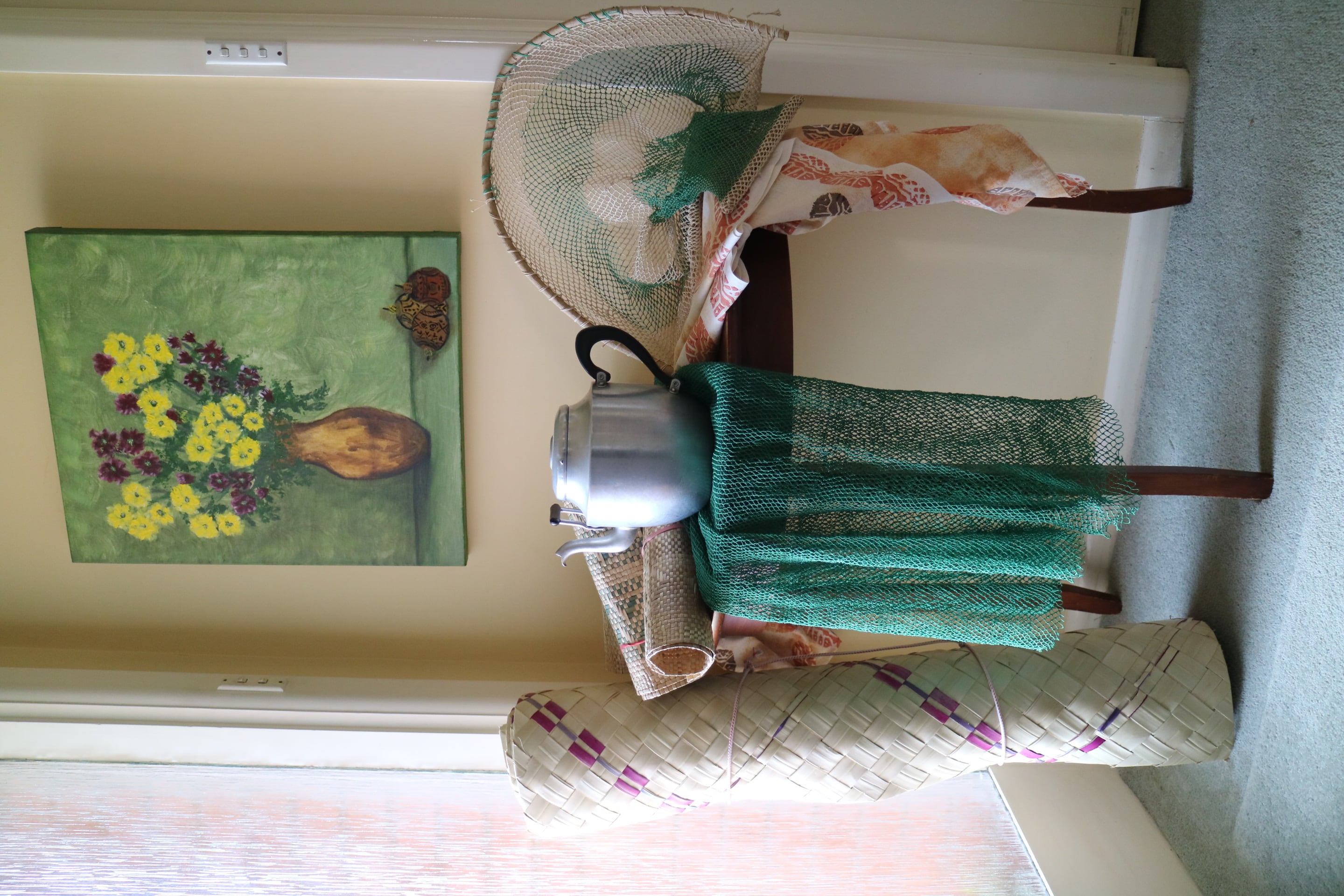 Table Instalment. The late Bubu Mummy Hannah Torome, Treasured Teapot, teapot, placemats, fishing nets; Kaukau cloth (1980) printed and hand painted by the late Aunty Pauline Panifasio.