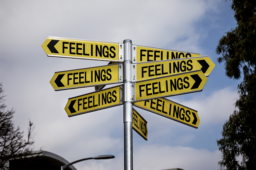 A street sign with several yellow signs pointed in many directions, against a blue sky. Each sign reads 'FEELINGS'.